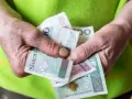 Dłonie trzymają polskie banknoty. Zastanawiasz się, ile wynosi renta socjalna?
