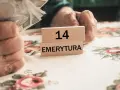 Dłonie trzymają pieniądze obok drewnianych klocków z napisem "14 EMERYTURA".