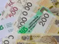 ZUS i polskie banknoty 200 i 500 zł. Legitymacja emeryta-rencisty ZUS leży na pieniądzach.