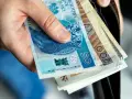 Dłoń trzyma polskie banknoty 50 i 200 zł. Zastanawiasz się nad nowymi zasadami przejścia na emeryturę? Tabela z wyliczeniami pomoże!