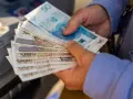 Ręce trzymające stos banknotów 200 zł i 50 zł. Zastanawiasz się, renta alkoholowa ile wynosi?