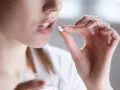 Kobieta bierze tabletkę clindamycin mip 600, trzymając szklankę wody.