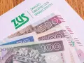 Koperta ZUS z banknotami 100 i 500 zł. Nadzieja na dodatkowe środki, jak trzynasta emerytura, dla seniorów.