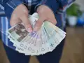 Dłonie trzymające plik polskich banknotów. Czy to zapłata za coś, czy może przyszła renta alkoholowa?