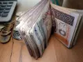 Stos banknotów 200 zł i monet obok kalkulatora. Czy to zapowiedź świadczenia pielęgnacyjnego 2026?