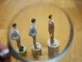 Figurki mężczyzn w garniturach stoją na stosach monet. Jedna z nich jest wyższa, symbolizując wyższe zarobki, podczas gdy pozostałe są niższe, odzwierciedlając średnią krajową.