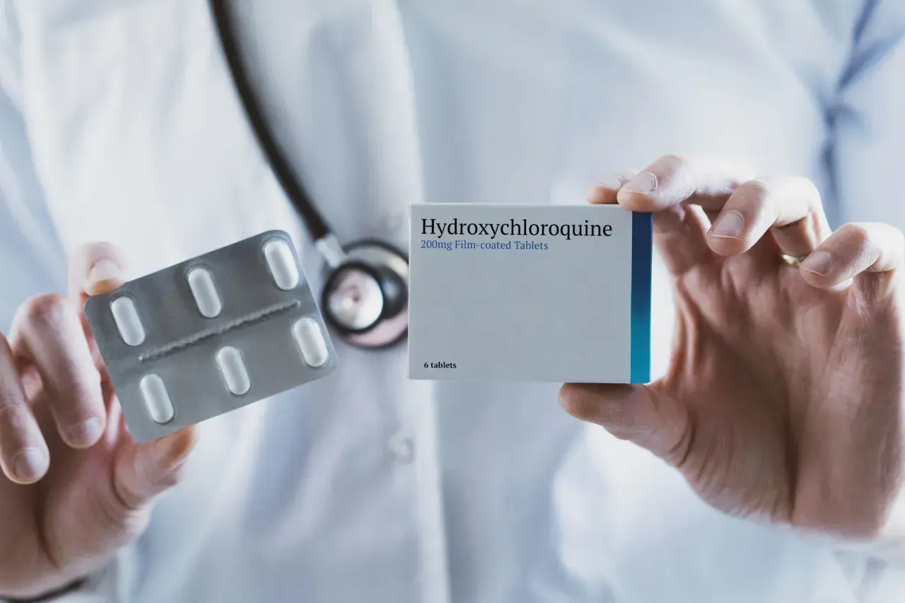 Lekarz prezentuje opakowanie leku Hydroxychloroquine 200mg i blister z tabletkami.