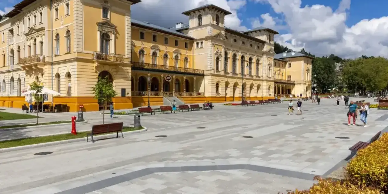 Plac przed sanatorium, gdzie obowiązują nowe zasady wyjazdu do sanatorium na NFZ. Ludzie spacerują po nowoczesnym deptaku.