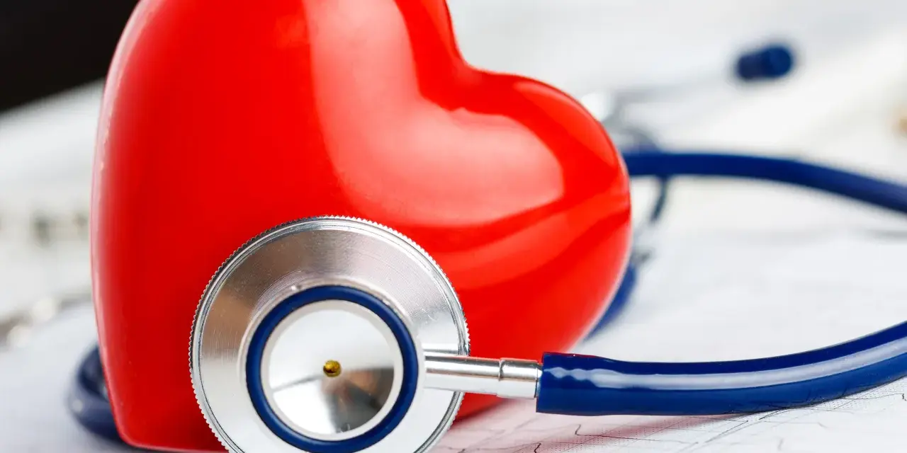 Czerwone serce i stetoskop na tle EKG. Symbolizuje troskę o zdrowie i prawidłowy poziom troponiny.