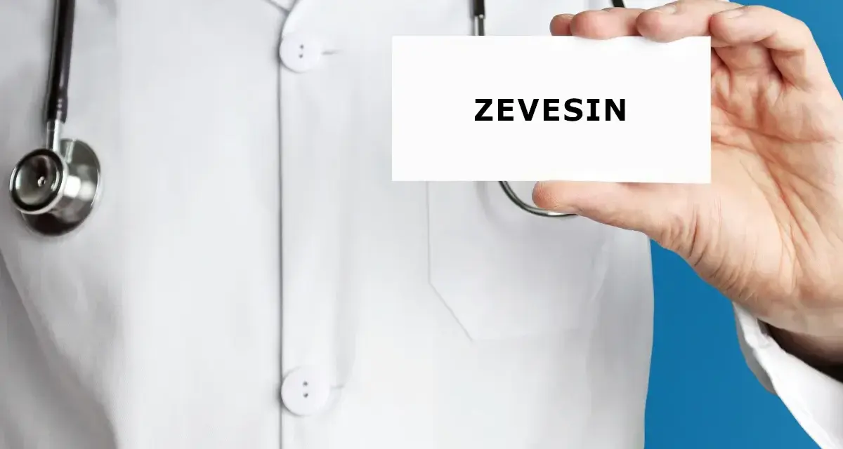 Lekarz w białym kitlu trzyma kartkę z napisem ZEVEISIN. Stetoskop wisi na jego szyi.