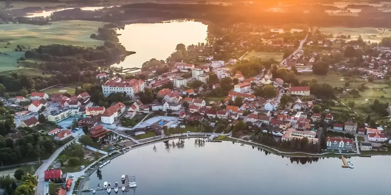 Malownicze miasteczko nad jeziorem o zachodzie słońca. Idealne miejsce na wykorzystanie bonu turystycznego i odpoczynek.