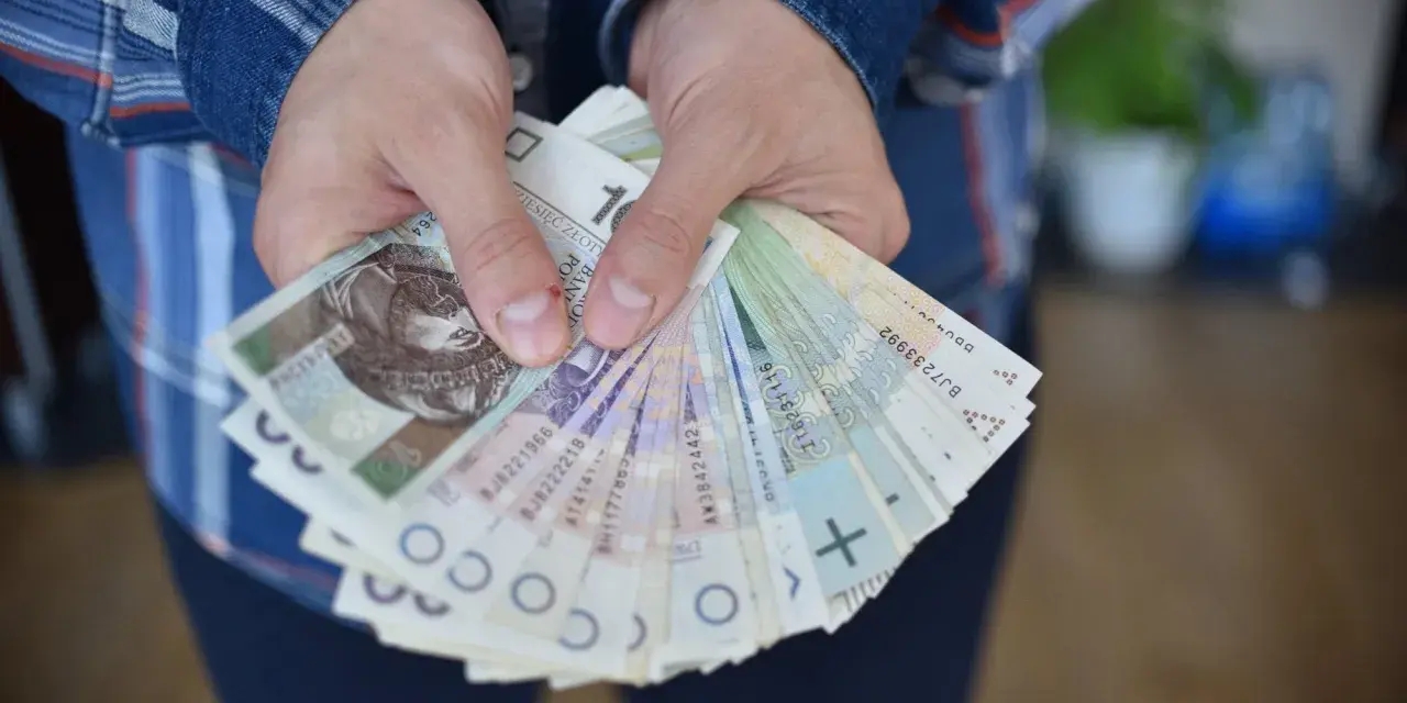Dłonie trzymające plik polskich banknotów. Czy to zapłata za coś, czy może przyszła renta alkoholowa?