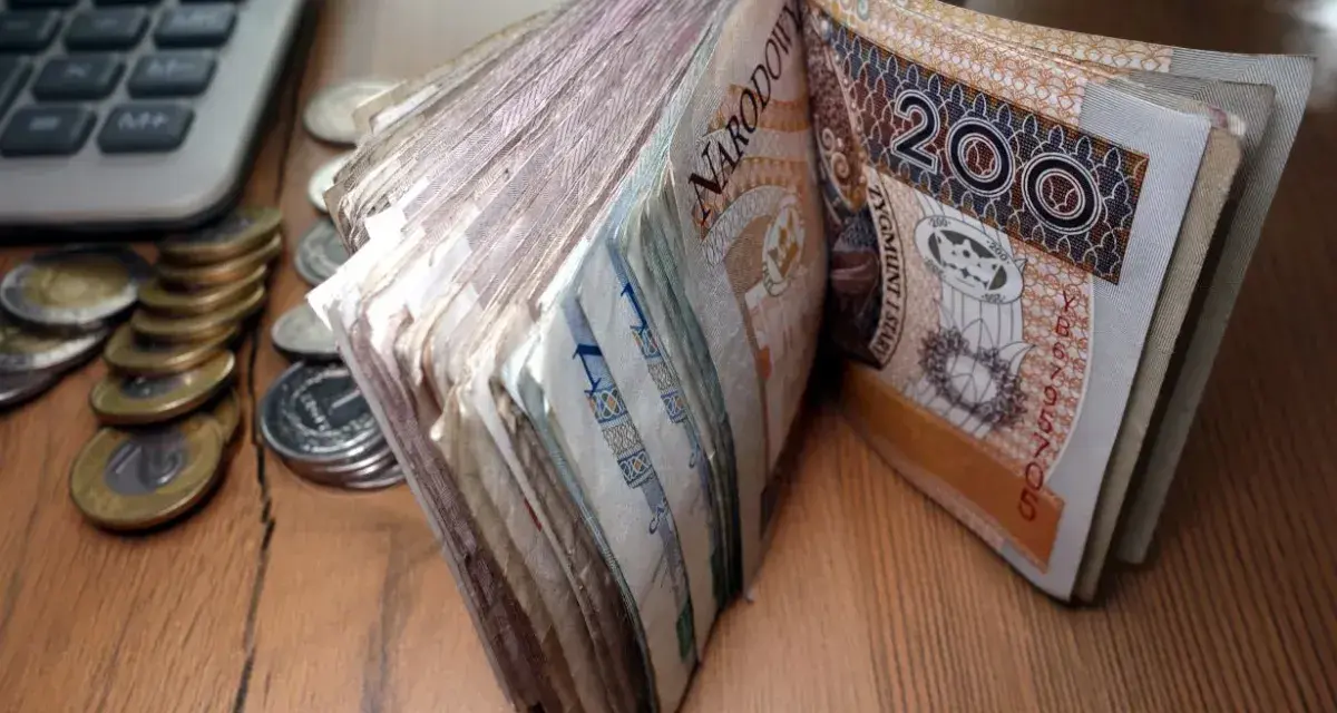 Stos banknotów 200 zł i monet obok kalkulatora. Czy to zapowiedź świadczenia pielęgnacyjnego 2026?