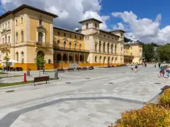 Plac przed sanatorium, gdzie obowiązują nowe zasady wyjazdu do sanatorium na NFZ. Ludzie spacerują po nowoczesnym deptaku.