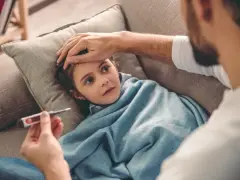 Ojciec mierzy gorączkę chorej córce. Czasem choroba to siła wyższa, która wpływa na kodeks pracy.