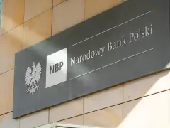 Tablica z godłem Polski i napisem "NBP Narodowy Bank Polski". Decyzje NBP wpływają na obniżkę stopy procentowej.