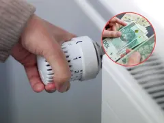 Ręka reguluje termostat grzejnika, a w tle widać polskie banknoty. To symbol oszczędzania na ogrzewaniu, być może dzięki bonowi ciepłowniczy.