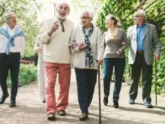 Grupa seniorów spaceruje po parku, ciesząc się świeżym powietrzem. Może rozmawiają o tym, jak przyjemnie jest płacić opłatę klimatyczną za takie widoki.