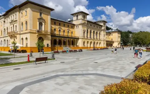 Plac przed sanatorium, gdzie obowiązują nowe zasady wyjazdu do sanatorium na NFZ. Ludzie spacerują po nowoczesnym deptaku.
