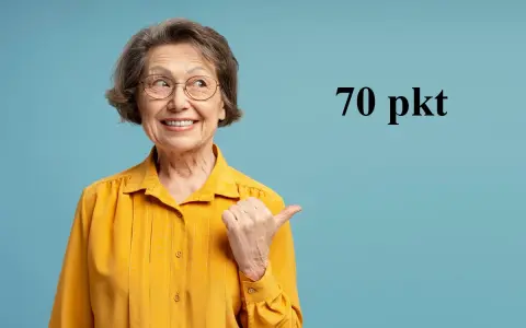 Uśmiechnięta starsza pani w żółtej bluzce wskazuje kciukiem na tekst "70 pkt", sugerując świadczenie wspierające punkty.