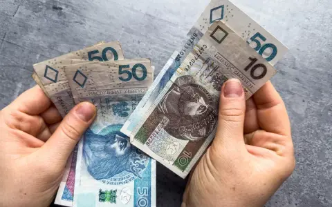 Dłonie trzymają polskie banknoty 10 i 50 zł. Może to symbolizować oczekiwanie na ponowne przeliczenie emerytury ZUS.