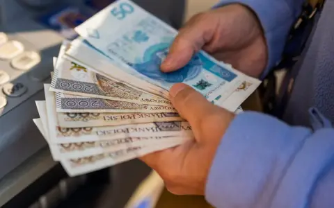Ręce trzymające stos banknotów 200 zł i 50 zł. Zastanawiasz się, renta alkoholowa ile wynosi?