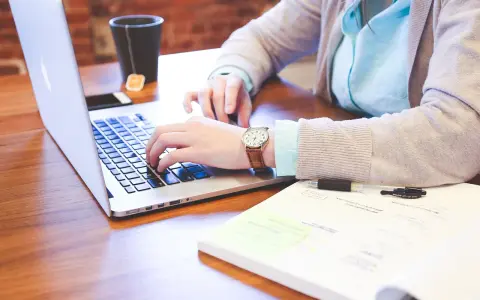 Kobieta pracuje na laptopie, analizując dokumenty. Może to być związane z rozliczeniem podatku od wzbogacenia.
