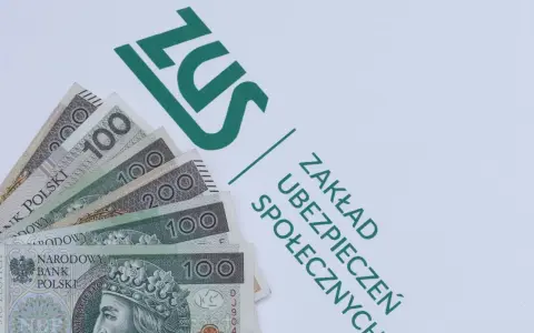 Pieniądze, w tym banknoty 100 i 200 zł, leżą obok zielonego logo ZUS. To dodatek dopełniający do świadczeń.