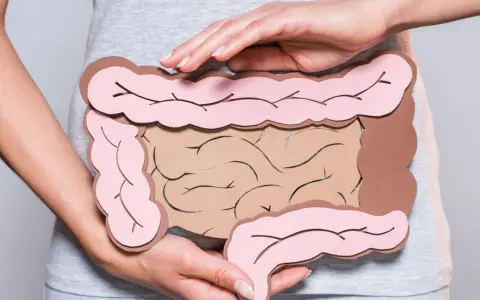 Dłonie obejmujące model jelit, symbolizujący problemy trawienne, takie jak śluz w kale.