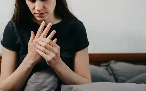Kobieta masuje dłoń, odczuwając drętwienie rąk w nocy.