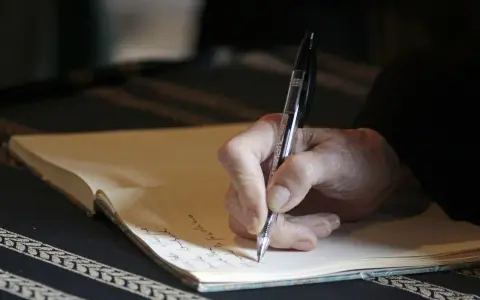 Dłoń pisze długopisem na kartce. Może to być ważny dokument, jak umowa dożywocia, podpisany w spokoju.