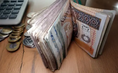 Stos banknotów 200 zł i monet obok kalkulatora. Czy to zapowiedź świadczenia pielęgnacyjnego 2026?