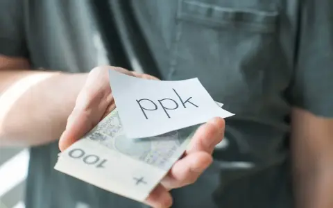 Dłoń trzyma banknoty i karteczkę z napisem "ppk". Jak sprawdzić swoje oszczędności?