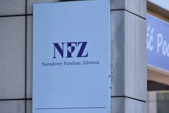 Tablica z logo NFZ (Narodowy Fundusz Zdrowia) i napisem "Narodowy Fundusz Zdrowia". Zapewnia dostęp do ubezpieczenia zdrowotnego.