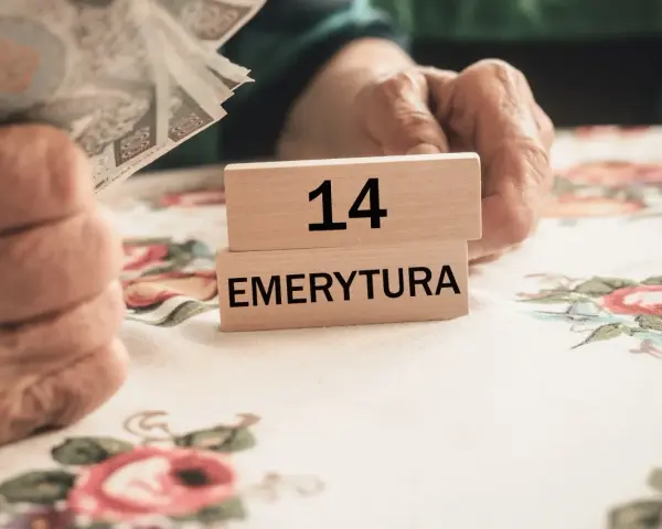 Dłonie trzymają pieniądze obok drewnianych klocków z napisem "14 EMERYTURA".