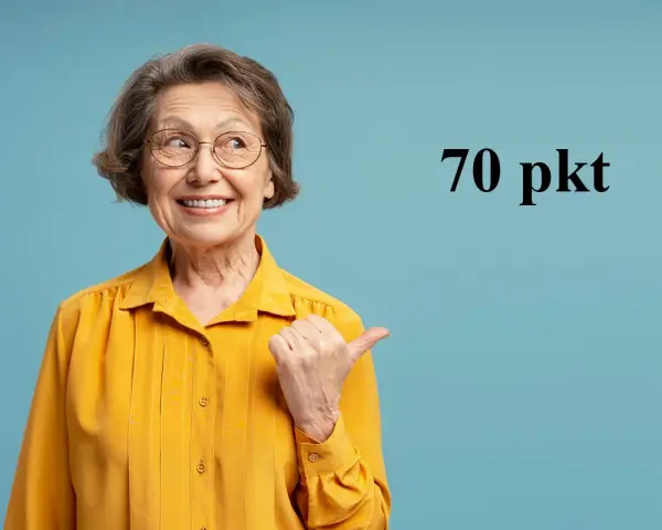 Uśmiechnięta starsza pani w żółtej bluzce wskazuje kciukiem na tekst "70 pkt", sugerując świadczenie wspierające punkty.