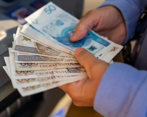 Ręce trzymające stos banknotów 200 zł i 50 zł. Zastanawiasz się, renta alkoholowa ile wynosi?