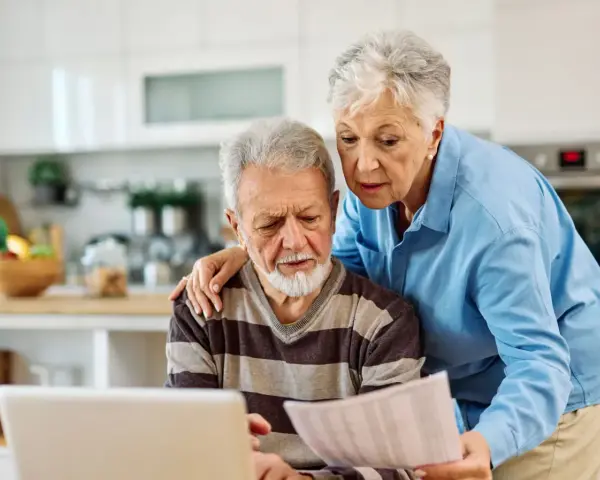Zmartwieni seniorzy analizują dokumenty, martwiąc się o najniższą emeryturę w Polsce.