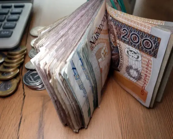 Stos banknotów 200 zł i monet obok kalkulatora. Czy to zapowiedź świadczenia pielęgnacyjnego 2026?