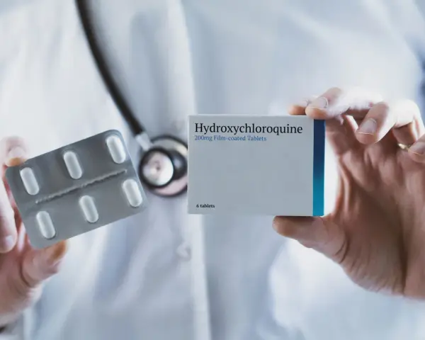 Lekarz prezentuje opakowanie leku Hydroxychloroquine 200mg i blister z tabletkami.