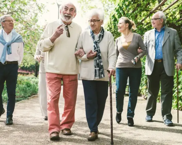 Grupa seniorów spaceruje po parku, ciesząc się świeżym powietrzem. Może rozmawiają o tym, jak przyjemnie jest płacić opłatę klimatyczną za takie widoki.