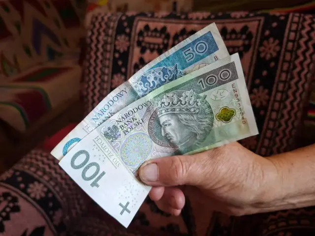Ręka trzyma banknoty 100 i 50 zł. To może być część środków na podlaski bon turystyczny 2026 na wakacje.
