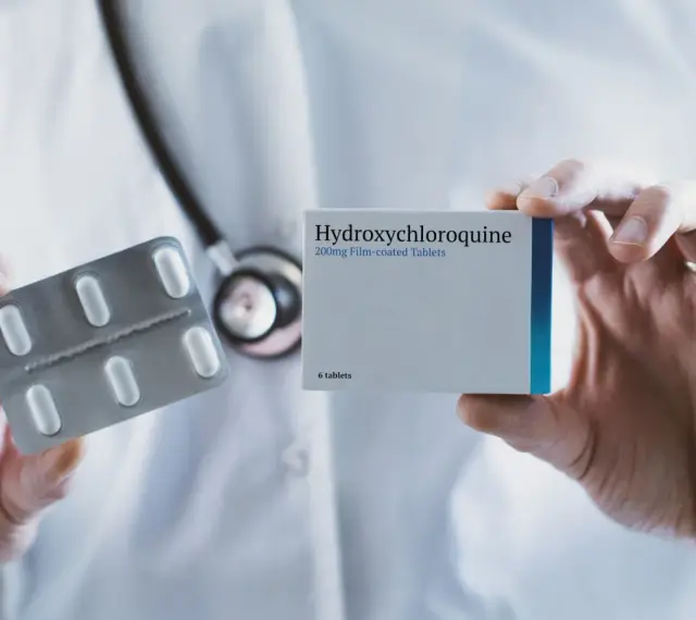 Lekarz prezentuje opakowanie leku Hydroxychloroquine 200mg i blister z tabletkami.