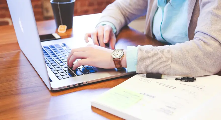 Kobieta pracuje na laptopie, analizując dokumenty. Może to być związane z rozliczeniem podatku od wzbogacenia.