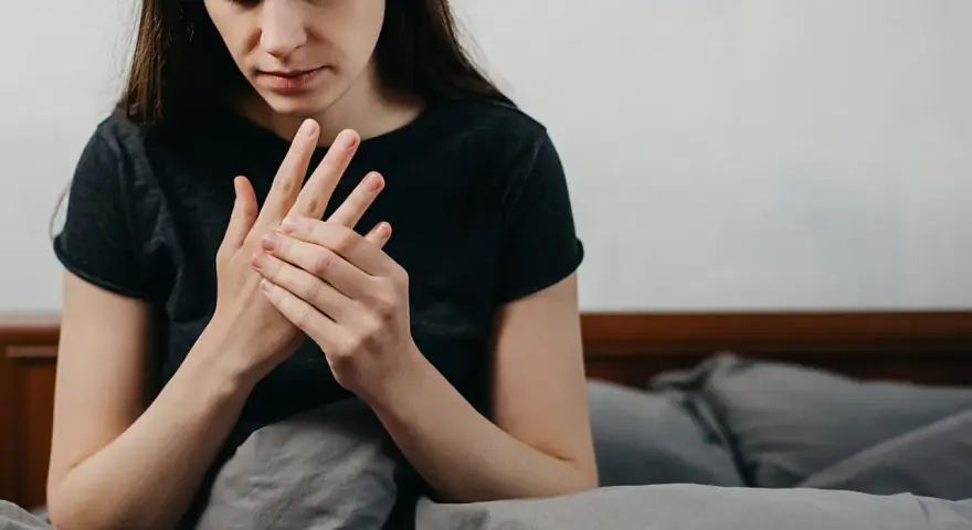 Kobieta masuje dłoń, odczuwając drętwienie rąk w nocy.