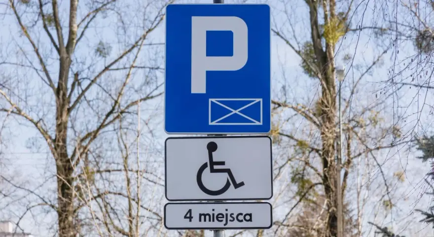 Znak informuje o parkingu dla osób z niepełnosprawnościami. Orzeczenie o niepełnosprawności można uzyskać na wiele chorób, np. schorzenia narządu ruchu.