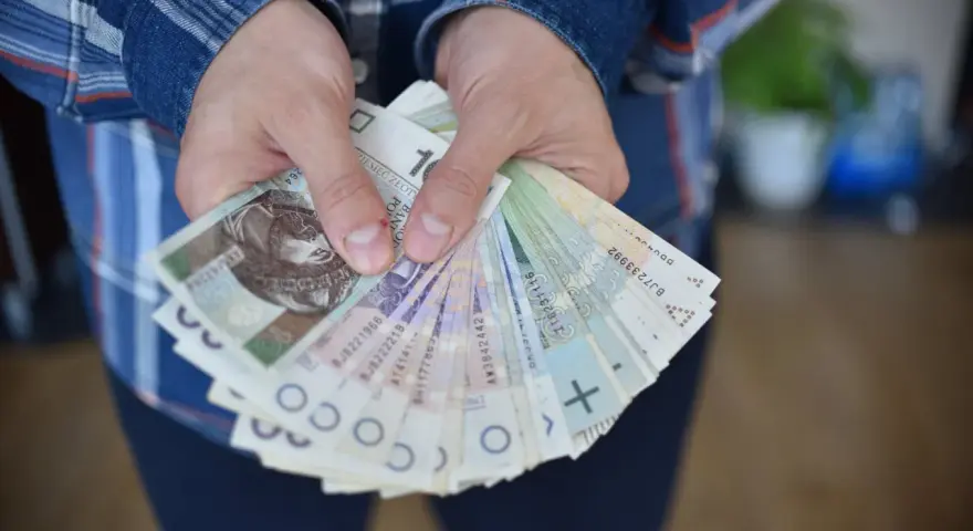 Dłonie trzymające plik polskich banknotów. Czy to zapłata za coś, czy może przyszła renta alkoholowa?