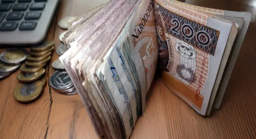 Stos banknotów 200 zł i monet obok kalkulatora. Czy to zapowiedź świadczenia pielęgnacyjnego 2026?