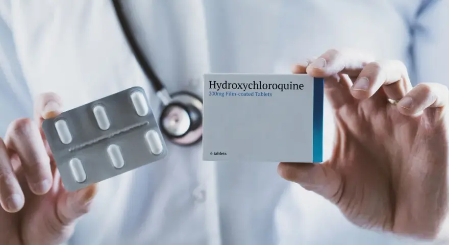 Lekarz prezentuje opakowanie leku Hydroxychloroquine 200mg i blister z tabletkami.