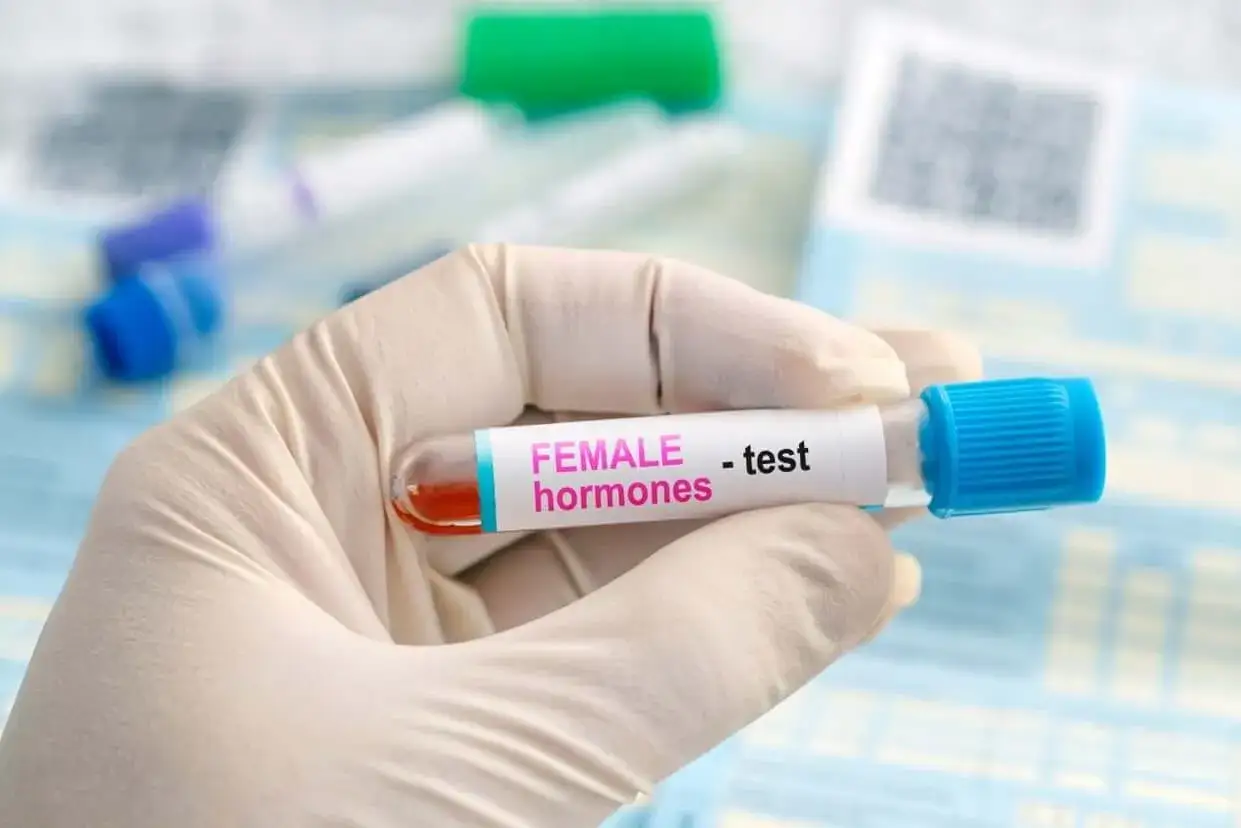 Ręka w rękawiczce trzyma probówkę z krwią do badania hormonów kobiecych, w tym FSH.